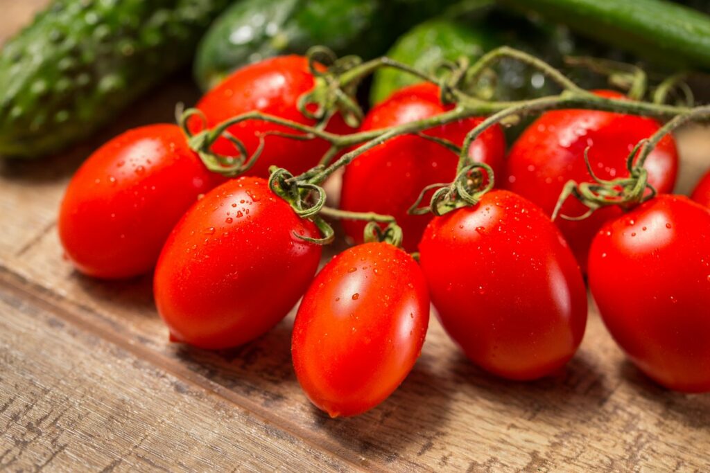 A bushel of ripe roma tomatoes rest on a table.