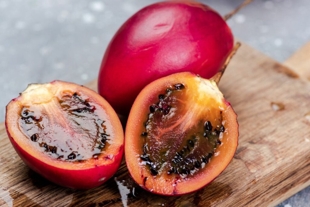 Harvested tamarillo cut open with back seeds inside