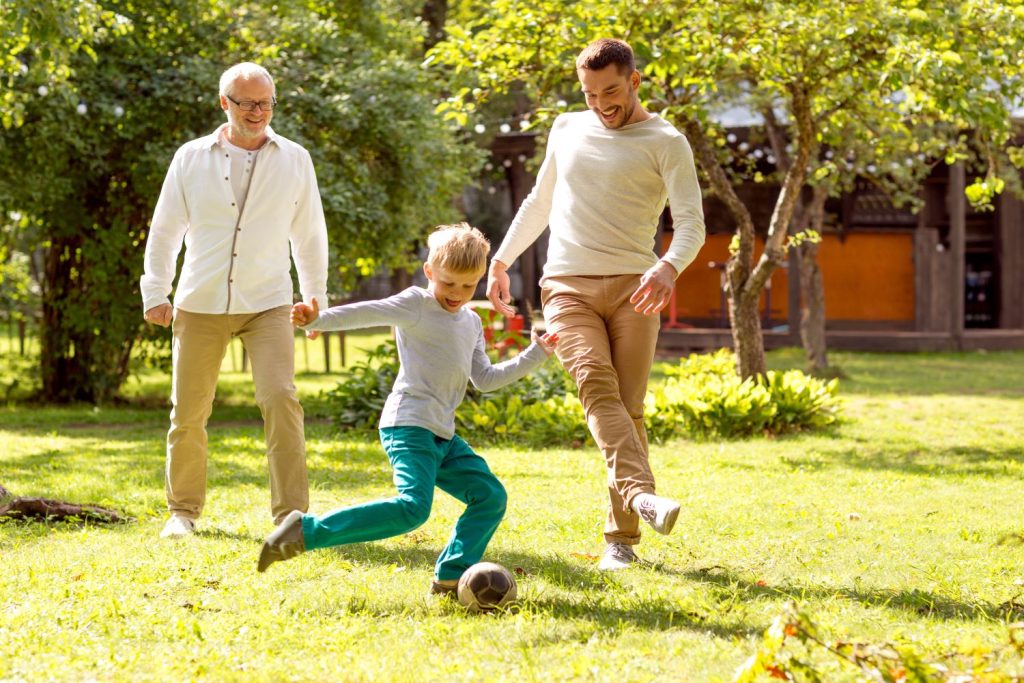 Grandfather, son and grandson playing football