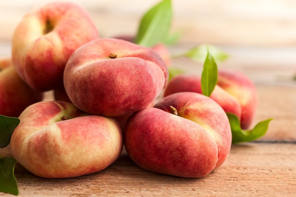 five flat peaches on a board